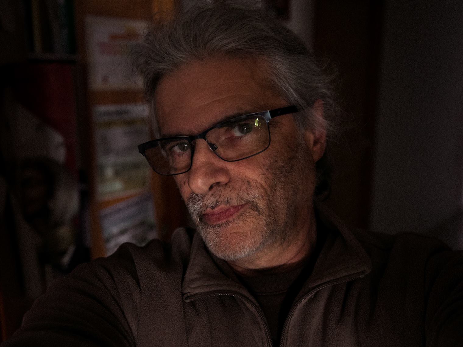 autoportrait en gros plan du photographe Benjamin Napolitano chez lui, ponano, ponanofoto, entrée du couloir, ambiance clair-obscur, visage éclairé, décor dans l'ombre