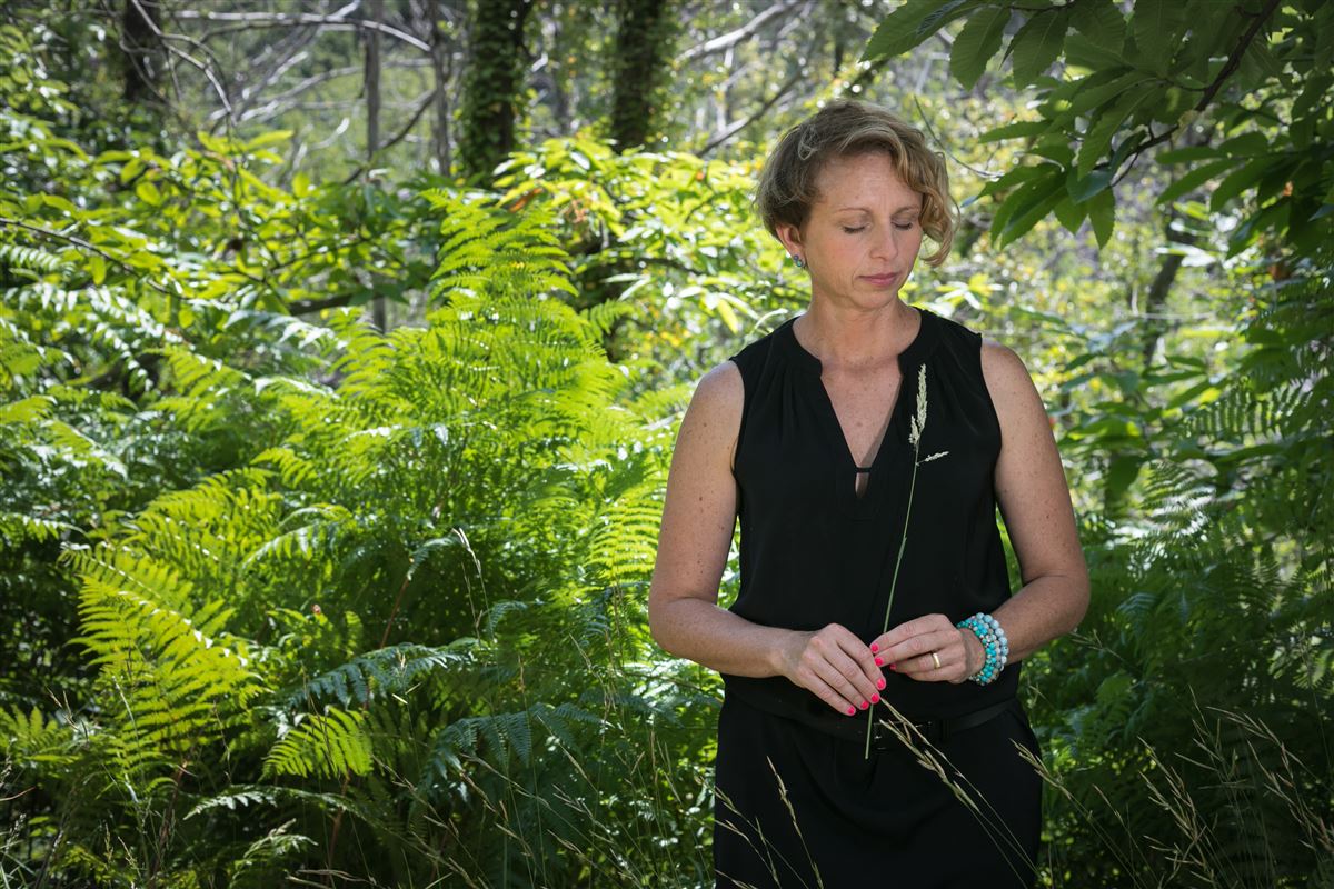 Elsa se ressource dans les bois, les yeux fermés, elle porte sa robe noire et tient une brindille dans les mains.